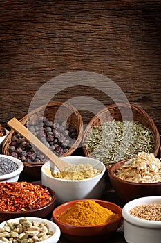 Different bowls of spices over a wooden background