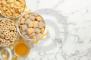 Different breakfast cereals and honey on marble table, flat lay. Space for text