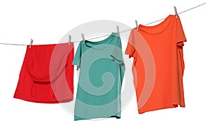 Different bright clothes drying on washing line against white background
