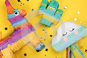Different bright pinatas on yellow background, flat lay photo