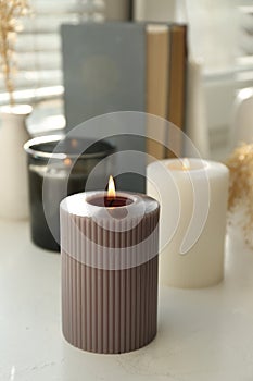 Different burning candles on window sill indoors