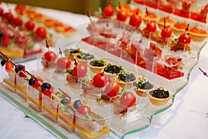 different canapes in cups with sauce and tartlets with black caviar.
