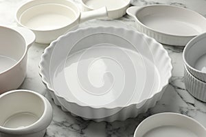 Different casseroles on white marble table, closeup