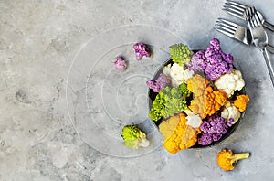 Different cauliflower cabbage on plate and grey concrete background with forks. Top view with copy space