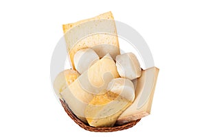 Different cheeses and a bunch of parsley lying in a wicker basket isolated on white background