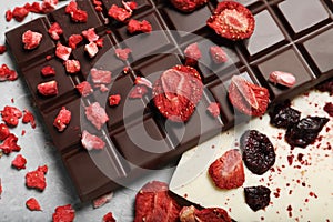 Different chocolate bars with freeze dried fruits on light marble table, closeup