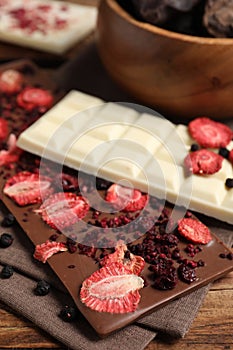 Different chocolate bars with freeze dried fruits on table, closeup