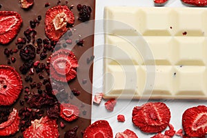 Different chocolate bars with freeze dried fruits on white wooden table, flat lay