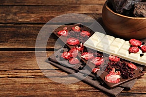 Different chocolate bars with freeze dried fruits on wooden table. Space for text