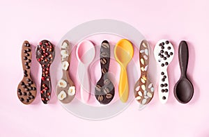 Different chocolote spoons are on a pink background