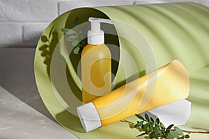 Different cleansers and leaves on grey table, space for text. Cosmetic product