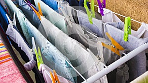 Different clothes hanging with colorful pins on the clotheshorse for drying on the balcony