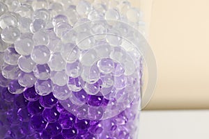 Different color fillers in glass vase, closeup. Water beads