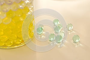 Different color fillers and glass vase on white table, closeup. Water beads