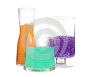 Different color fillers in glass vases isolated on white. Water beads