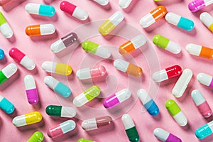Different color pills on a pink background