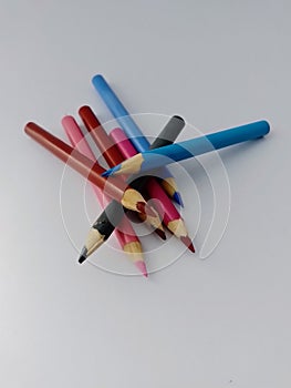 Different colored pencil crayons in a pile on a white background