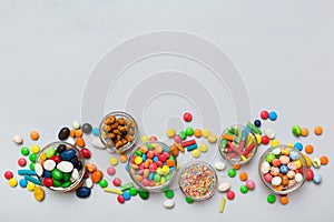 different colored round candy in bowl and jars. Top view of large variety sweets and candies with copy space