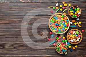 different colored round candy in bowl and jars. Top view of large variety sweets and candies with copy space