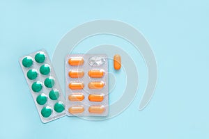 Different colored tablets, pills, capsule medicines blister packs, on blue background. Health care concept. Copy space.