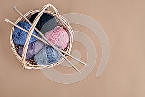 Different colored yarn in basket with knitting needles. Top view