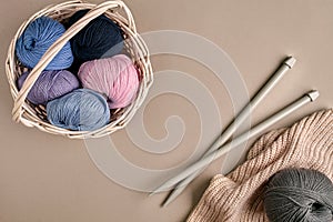 Different colored yarn in basket with knitting needles. Top view