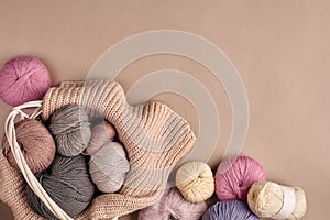 Different colored yarn in basket with knitting needles. Top view