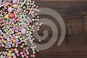 Different colorful beads on the brown wooden table