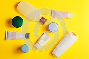 Different colorful beauty toiletries on yellow background. men and women care products for hair and body. Top view photo