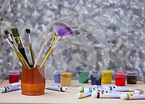 Different colorful brushes on the table, wooden background