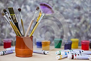 Different colorful brushes on the table, wooden background