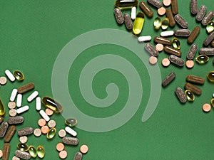 Different colorful dietary supplements on green background.