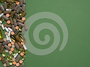 Different colorful dietary supplements on green background.