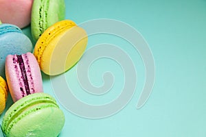 Different colorful macaroons on blue background. Free space for text