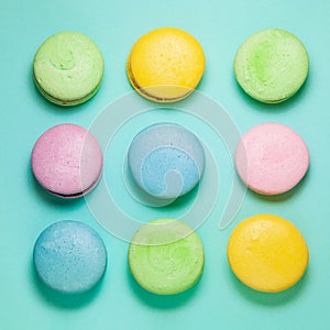 Different colorful macaroons on blue background. Square form