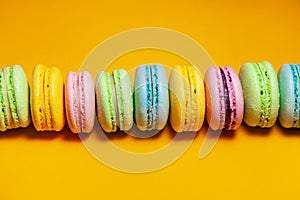 Different colorful macaroons on orange background