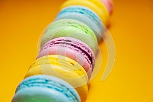 Different colorful macaroons on orange background