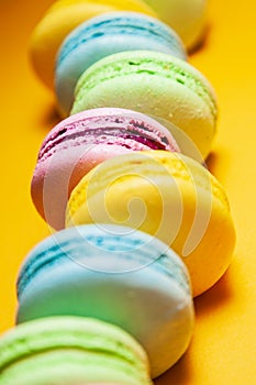 Different colorful macaroons on orange background