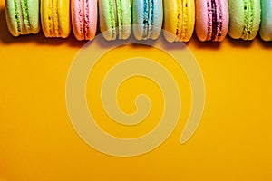 Different colorful macaroons on orange background. Free space for text