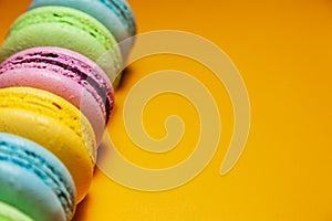 Different colorful macaroons on orange background. Free space for text