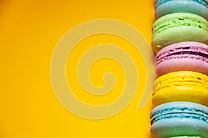 Different colorful macaroons on orange background. Free space for text