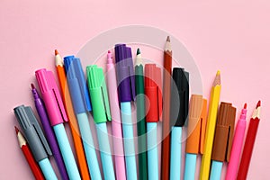 Different colorful pencils and felt tip pens on pink background, flat lay. Diversity concept