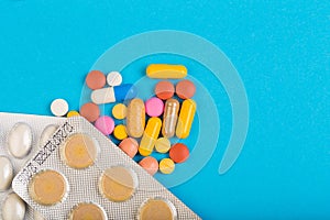 Different colorful pills and plastic packs - blisters stacked on blue abackground