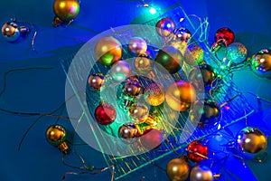 Different colors balls, lights are on the glass plate on the blue table/background. Merry Christmas/Happy New Year 2020.