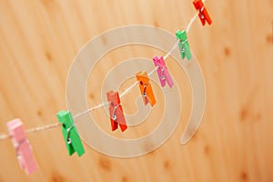 Different colors clothespins on rope with wooden backdrop, abstract background