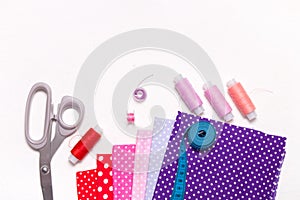 Different colors of fabric with a pattern, scissors and spools of thread