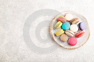 Different colors macaroons on ceramic plate on gray concrete background. top view, copy space
