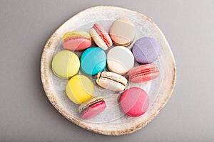 Different colors macaroons on ceramic plate on gray pastel background. side view, close up