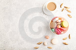 Different colors macaroons and chocolate eggs in ceramic bowl, cup of coffee on gray concrete background. top view, copy space