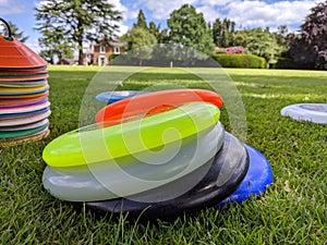 Different coloured ultimate frisbees piled up on the grass